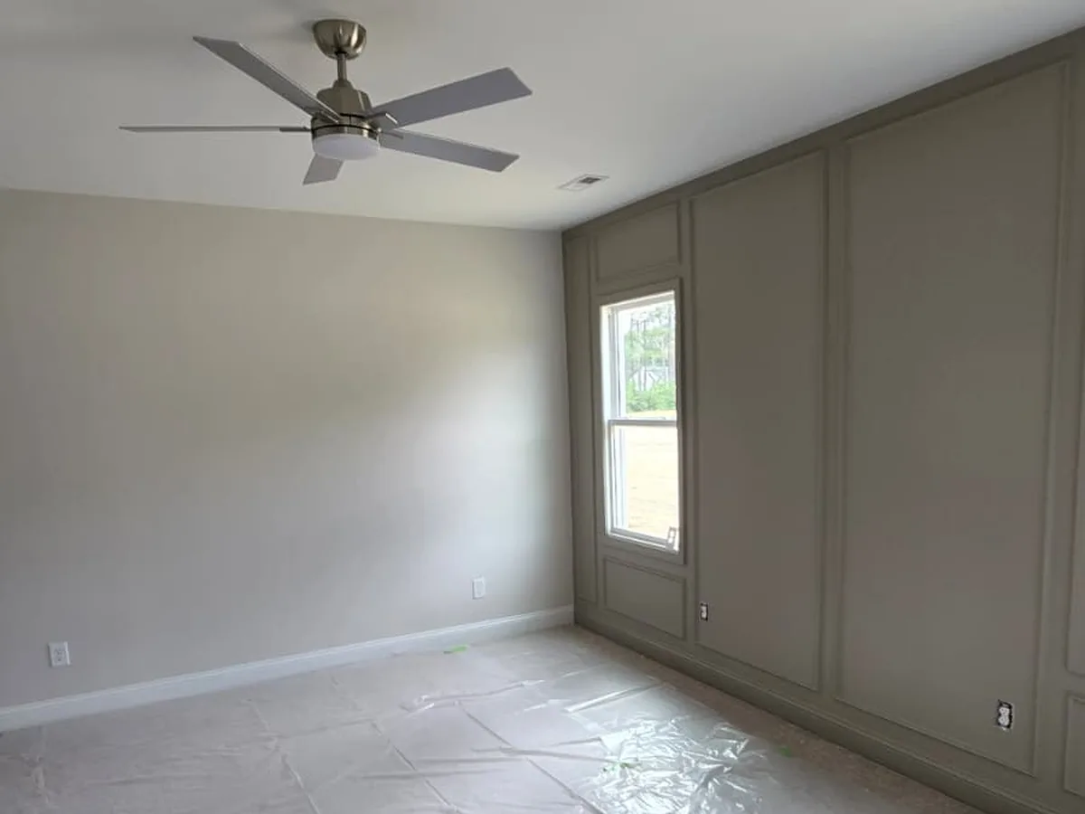Freshly painted living room with a ceiling fan and the floor covered for protection